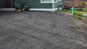 A green building with a garage, a lawn, and a wooden deck.