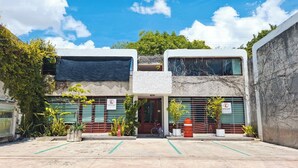 A two-story building with a covered entrance, potted plants, and a bicycle parked outside. - Apartment great location convenient parking (Mérida)