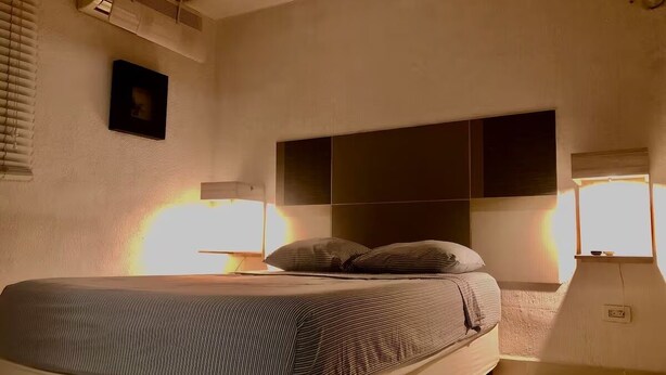 A bedroom with a bed, bedside lamps, a wall-mounted air conditioner, and a framed picture. - Apartment great location convenient parking (Mérida)