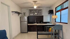 A compact kitchen with a refrigerator, stove, and dining area with a table and chairs. - Apartment great location convenient parking (Mérida)