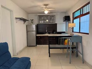 A compact kitchen with a refrigerator, stove, and dining area with a table and chairs. - Apartment great location convenient parking (Mérida)