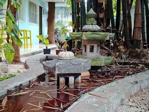 A traditional stone water feature with tiered structures, surrounded by bamboo and potted plants. - Apartment great location convenient parking (Mérida)