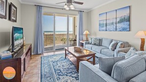 A living room with a sofa, a coffee table, a TV, and a balcony with a view. - 3rd Floor ~ Amazing Views (Dauphin Island)