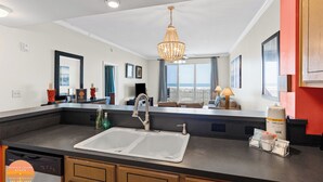 A modern kitchen with a large sink, a chandelier, and a view of the ocean. - 3rd Floor ~ Amazing Views (Dauphin Island)