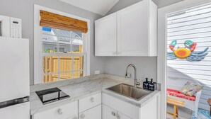 A kitchen with white cabinets, a built-in stove, a sink, and a window with a view of a wooden deck. - Key West Steps to Duval, Truman Waterfront Park and Beach. Walk everywhere (Key West)