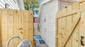 A wooden deck with a bird sculpture, a door, and a small table with a blue mat. - Key West Steps to Duval, Truman Waterfront Park and Beach. Walk everywhere (Key West)