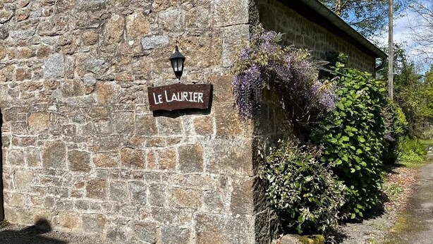 Un bâtiment en pierre avec une enseigne indiquant « Le Laurier » et une petite fenêtre au-dessus.