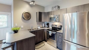 Uma cozinha moderna com uma ilha central, eletrodomésticos de aço inoxidável e um relógio decorativo na parede.