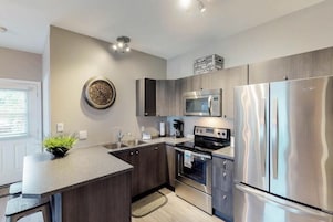Uma cozinha moderna com uma ilha central, eletrodomésticos de aço inoxidável e um relógio decorativo na parede.