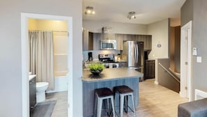 Uma cozinha moderna com ilha central, eletrodomésticos de aço inoxidável e um pequeno espaço de bar.