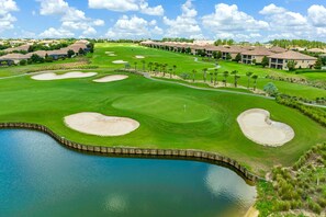 A golf course with bunkers, a water body, and residential buildings in the background. - Lakefront Family Escape with Pool | Near Disney (Davenport)