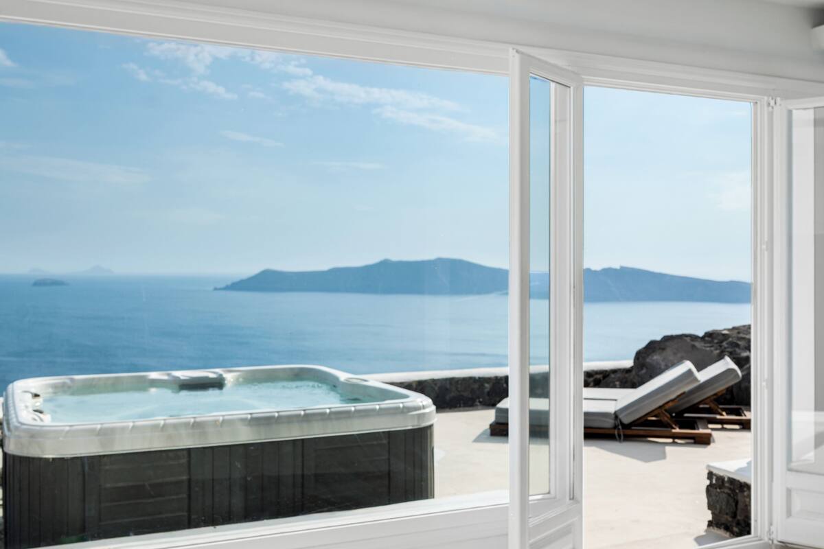 A hot tub on a balcony with a view of the sea and mountains.