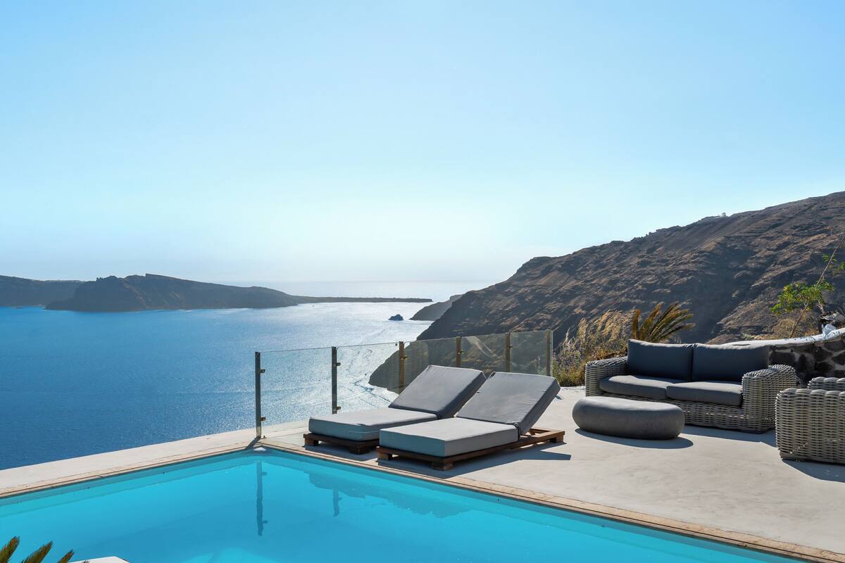 A pool with lounge chairs and a view of the sea.