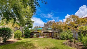 A residential property with a fenced yard, a covered patio, and a house with a green roof. - Gulf Gate Getaway (Sarasota)