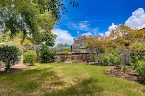 A residential property with a fenced yard, a covered patio, and a house with a green roof. - Gulf Gate Getaway (Sarasota)