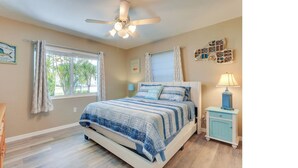 A bedroom with a bed, a nightstand, a ceiling fan, and a window with curtains. - Gulf Gate Getaway (Sarasota)