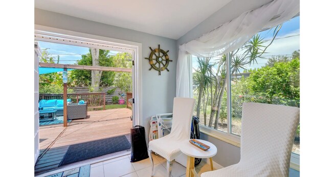 A room with a view of a pool, a sail wheel decoration, and a small table with a chair. - Gulf Gate Getaway (Sarasota)