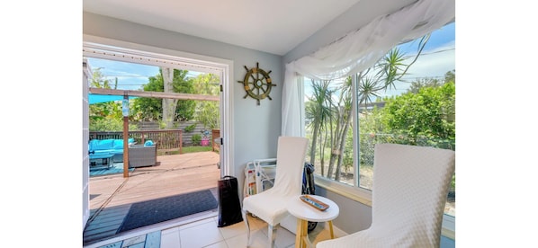 A room with a view of a pool, a sail wheel decoration, and a small table with a chair. - Gulf Gate Getaway (Sarasota)
