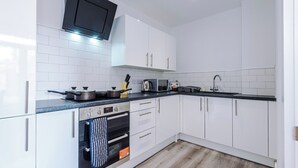 A modern kitchen with white cabinets, a black countertop, and a built-in oven. - Middleton Chambers by Guestz (Hull)