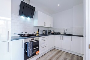 A modern kitchen with white cabinets, a black countertop, and a built-in oven. - Middleton Chambers by Guestz (Hull)