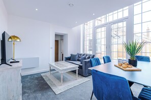 A modern living room with a sofa, coffee table, and dining table with chairs. - Middleton Chambers by Guestz (Hull)