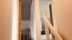 A staircase leading to a room with a chair and a window with blinds. - Vacation apartment "Utkiek" in Greetsiel (50 sqm / 2-3 persons) (Krummhörn)
