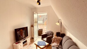 A living room with a television, sofa, armchair, coffee table, and a lamp. - Vacation apartment "Utkiek" in Greetsiel (50 sqm / 2-3 persons) (Krummhörn)