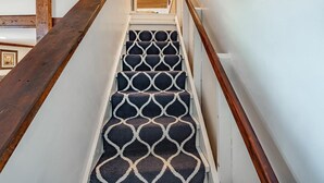 A staircase with a geometric patterned carpet, wooden handrails, and a wooden floor. - Boho Blue Heron, BBH 7532 (Birch Bay)
