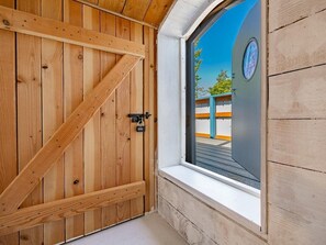 A wooden door with a lock and a window with a view of a building and trees. - Boho Blue Heron, BBH 7532 (Birch Bay)