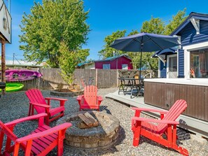A backyard with red Adirondack chairs, a fire pit, and a table with chairs. - Boho Blue Heron, BBH 7532 (Birch Bay)