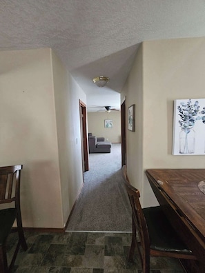 A hallway with a dining table and chairs, a ceiling fan, and a sofa in the background.