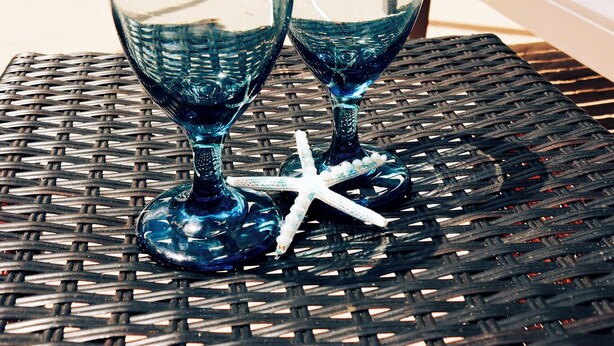 A poolside setting with two clear glasses and a starfish on a woven table. - Relaxing & inviting pool house (Spring Hill)