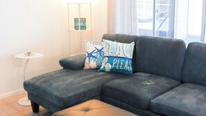 A modern living room with a sectional sofa, an ottoman, a small side table, and a lamp. - Relaxing & inviting pool house (Spring Hill)