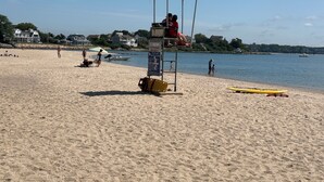 En strand med ett livräddartorn, en gul kajak och en livräddarstol.