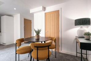 A dining area with a round table, four chairs, a potted plant, and a lamp. - Middleton Chambers by Guestz (Hull)