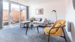 Una sala de estar moderna con un sofá, un sillón, una mesa de centro y una lámpara de pie.