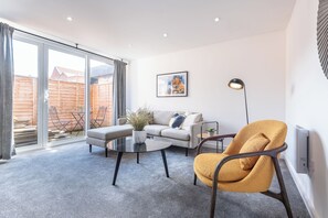 A modern living room with a sofa, armchair, coffee table, and a floor lamp. - Middleton Chambers by Guestz (Hull)