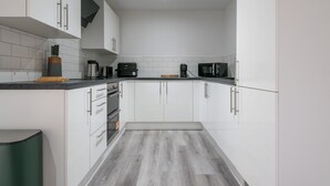 Una cocina moderna con armarios blancos, encimera negra y un microondas.