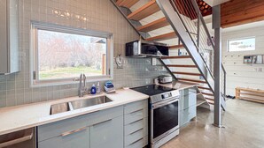 Eine moderne Küche mit Backofen, Spüle aus Edelstahl und einer Holztreppe.