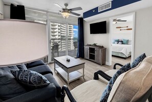 Ein Balkon mit Tisch und Stühlen, ein an der Wand befestigter Fernseher und ein Bett mit Kissen.