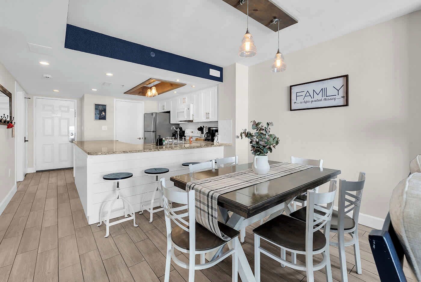 A modern kitchen with white cabinetry, a central island, and pendant lighting.
