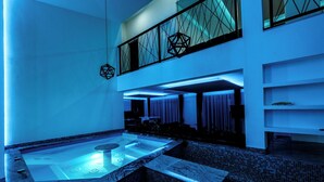 Un'area spa moderna con vasca idromassaggio, posti a sedere e un soffitto con motivi geometrici.