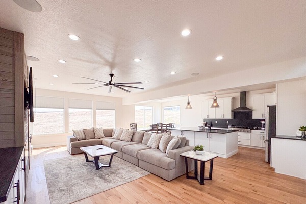 Bright open living space with sectional sofa, modern kitchen, and expansive mountain‑view windows