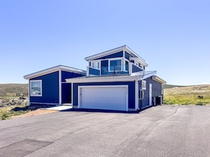 A two-story house with a garage, a small attached shed, and a clear driveway.