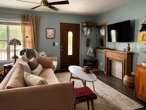 Ein Wohnzimmer mit Sofa, Tisch, Kamin, Fernseher und Deckenventilator.