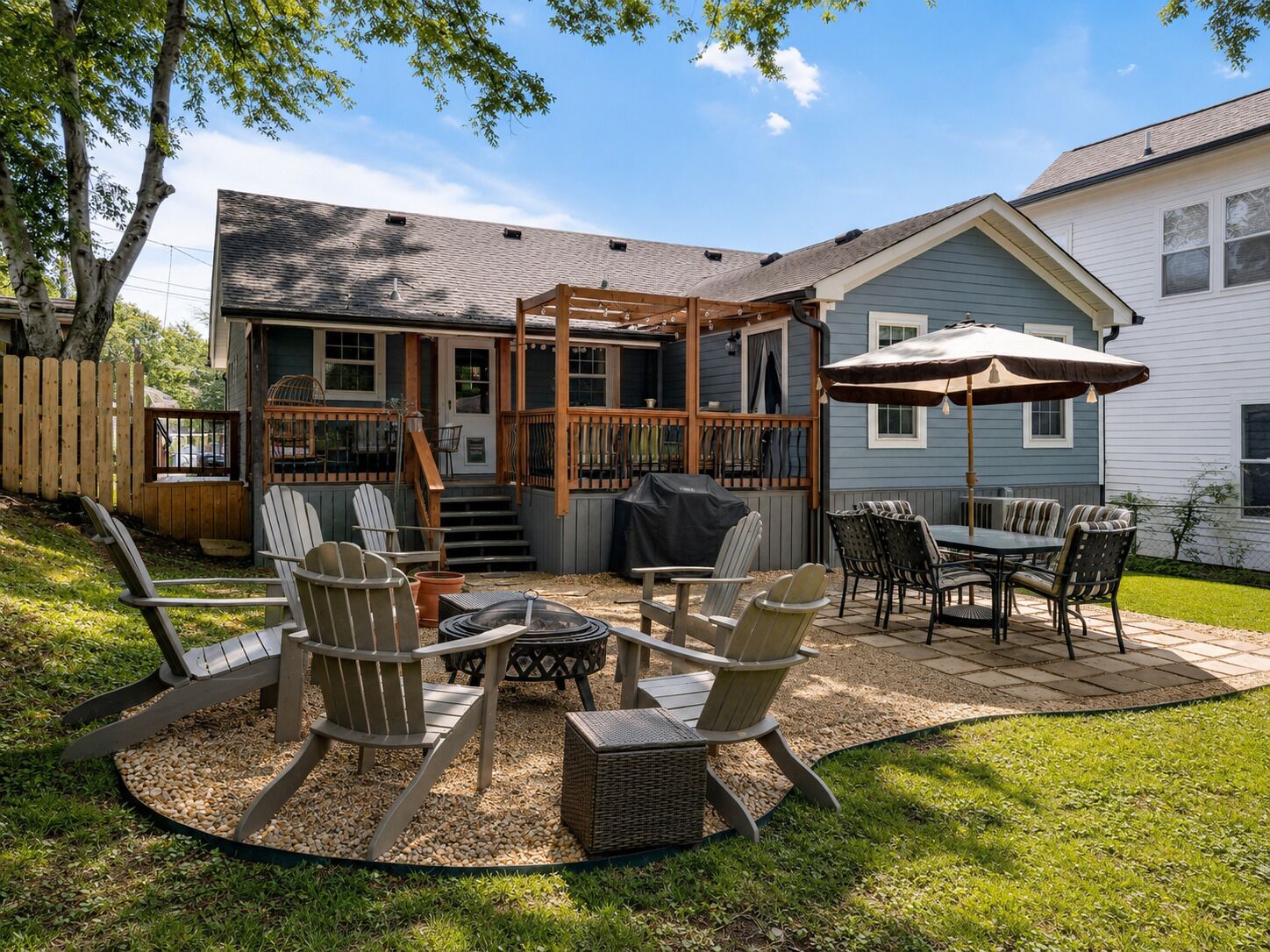 Un jardin avec un patio couvert, un espace salon extérieur et un barbecue.