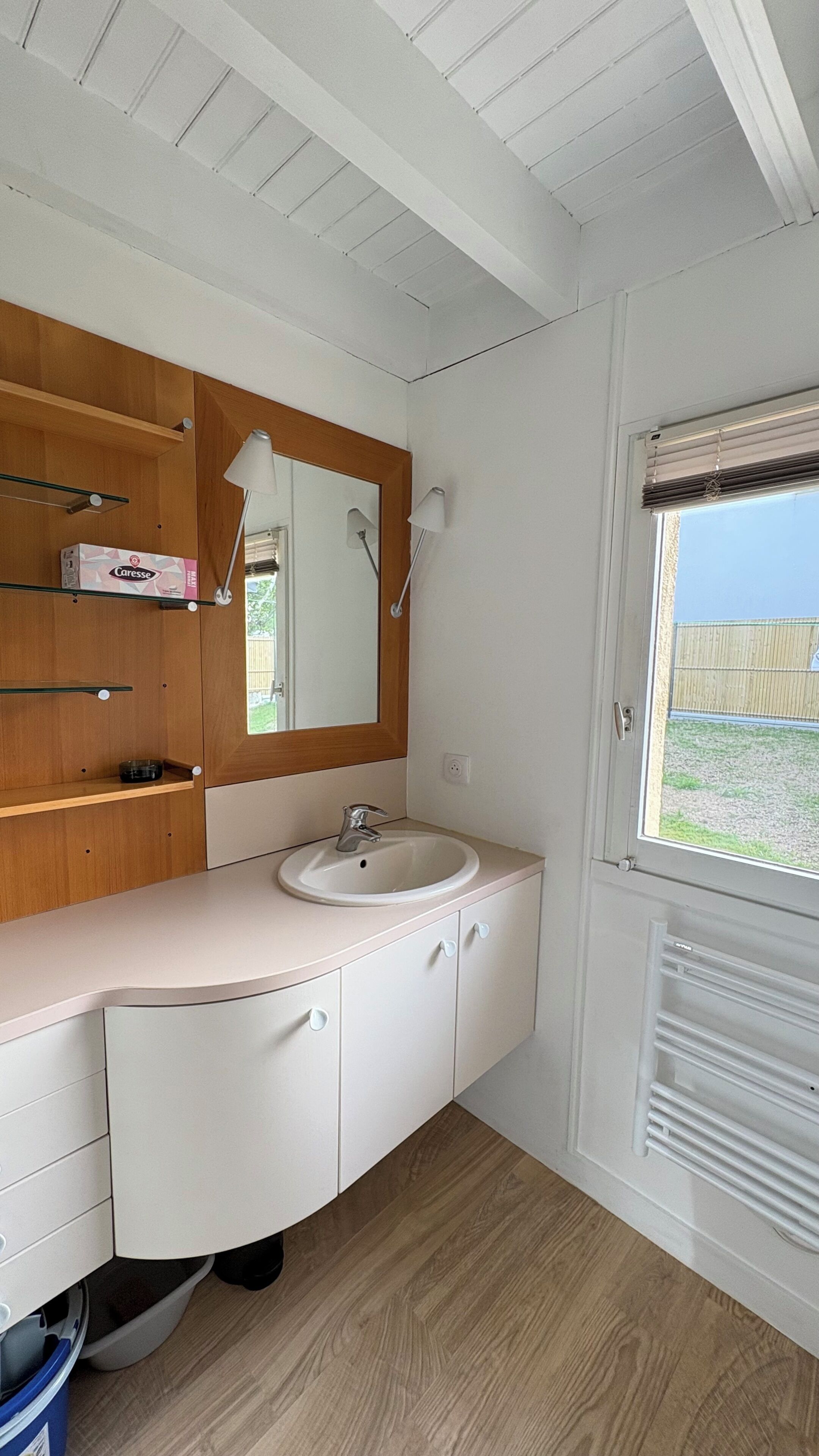 A compact bathroom with a sink, mirror, and wooden vanity.