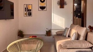 Una sala de estar con un sofá, un sillón, un televisor y obras de arte en la pared.