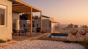 Un patio exterior moderno con piscina, mobiliario y vistas al paisaje.