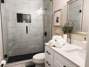 Une salle de bain équipée d’une douche, de toilettes, d’un lavabo et d’un miroir.
